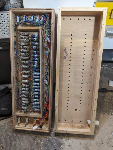 Two open wooden organ wind chests with wiring and many blue electromagnets in a workshop