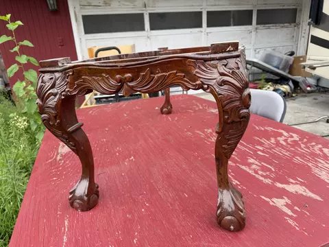 Ornate carved wooden table base outdoors