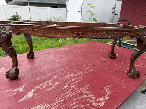 Ornate wooden coffee table outdoors near a white wall