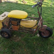 Vintage yellow Cushman scooter with seat parked on grass outdoors