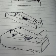 Pen sketch of wooden instrument concepts on lined paper.